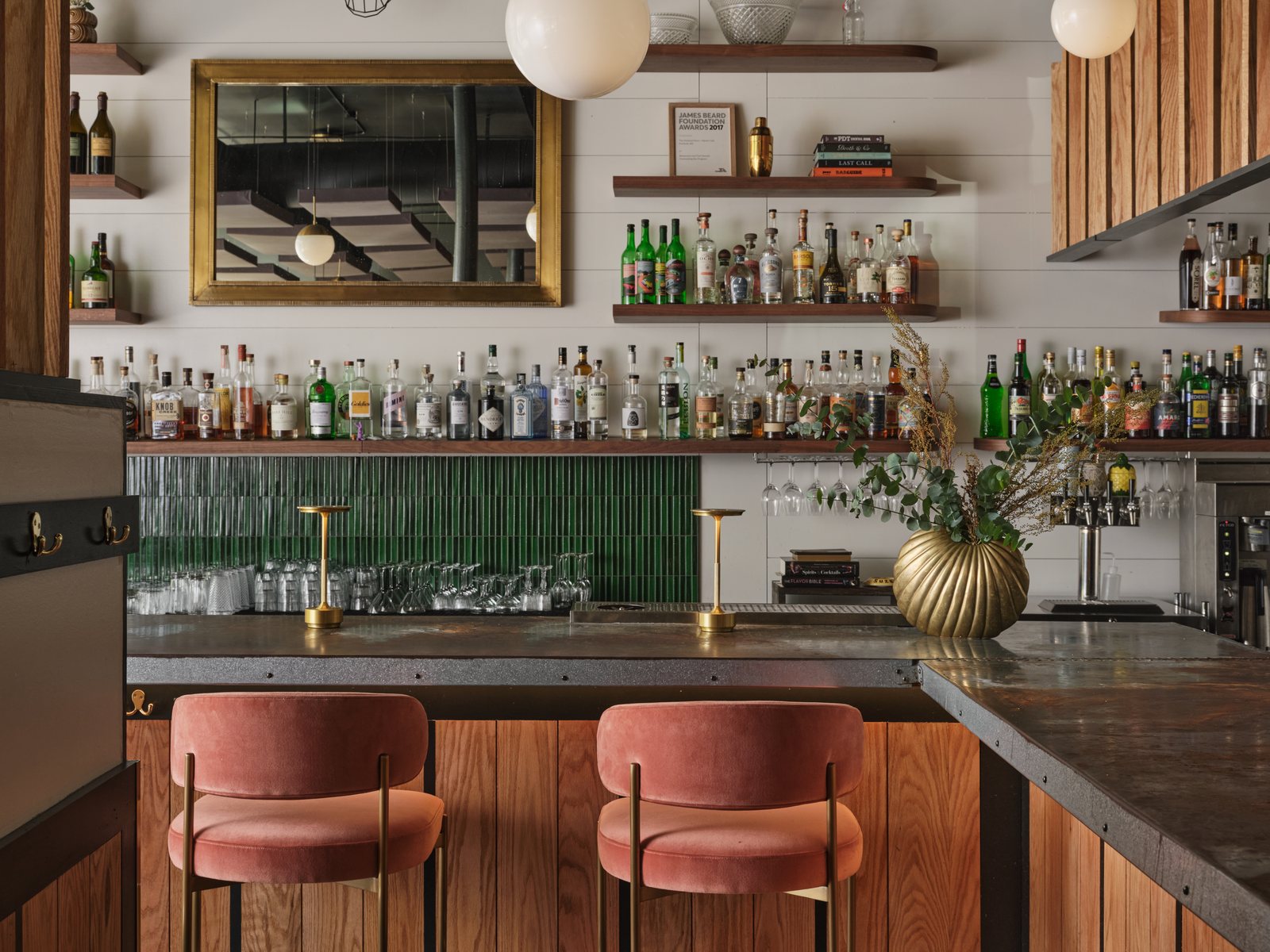 The back bar at Hunt & Alpine, with green tile, brass lamps and pink velvet stools